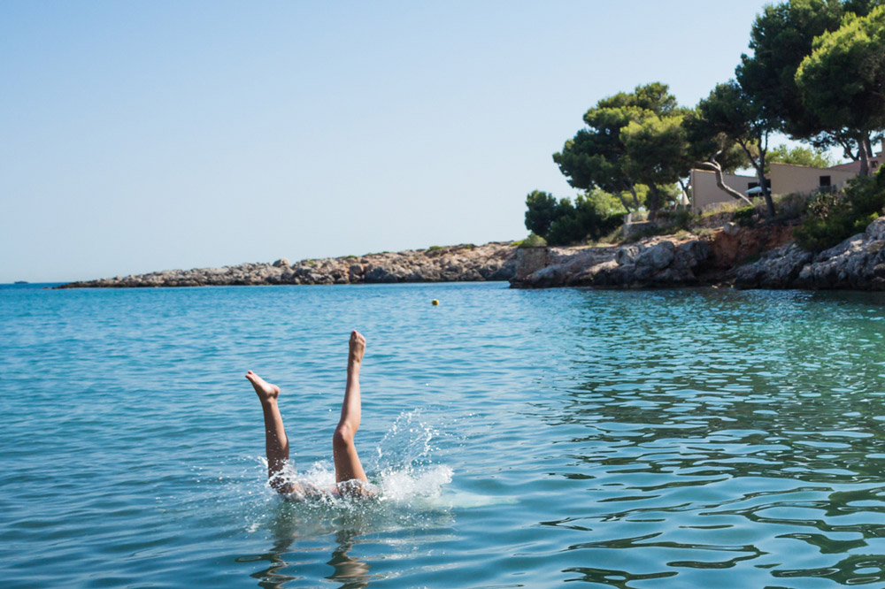 A young woman is doing a handstand in the sea.