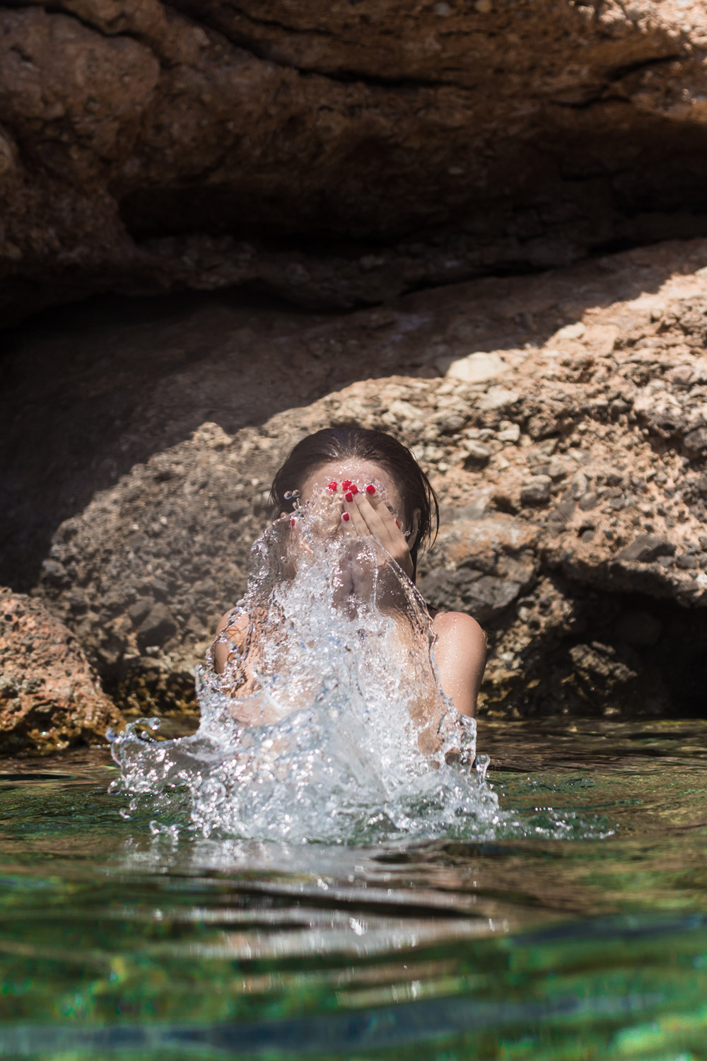Una mujer joven en el mar, echándose agua a la cara.